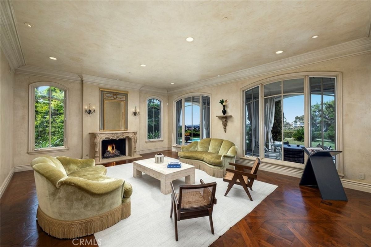 A family room with windows, a fireplace, couches, chairs, and a center table.