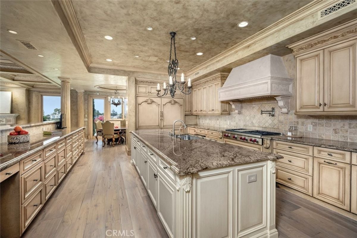 A kitchen with a center island, chandelier, countertops, cabinets, a sink, and a stove.