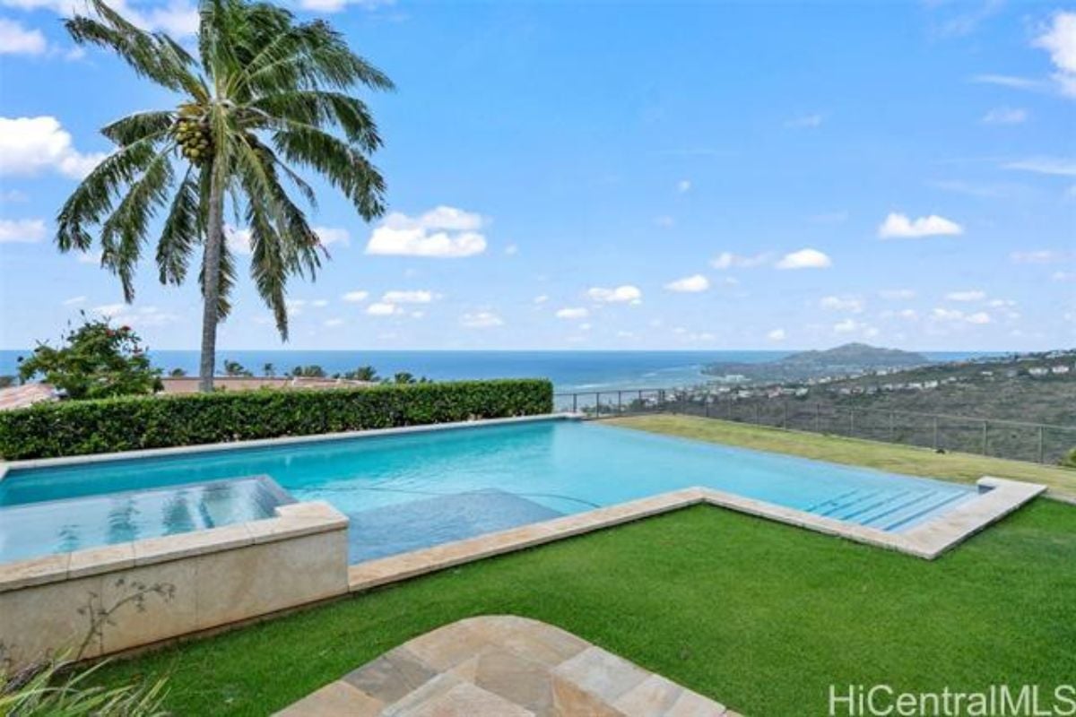A swimming pool with a jacuzzi, surrounded by lush plants.