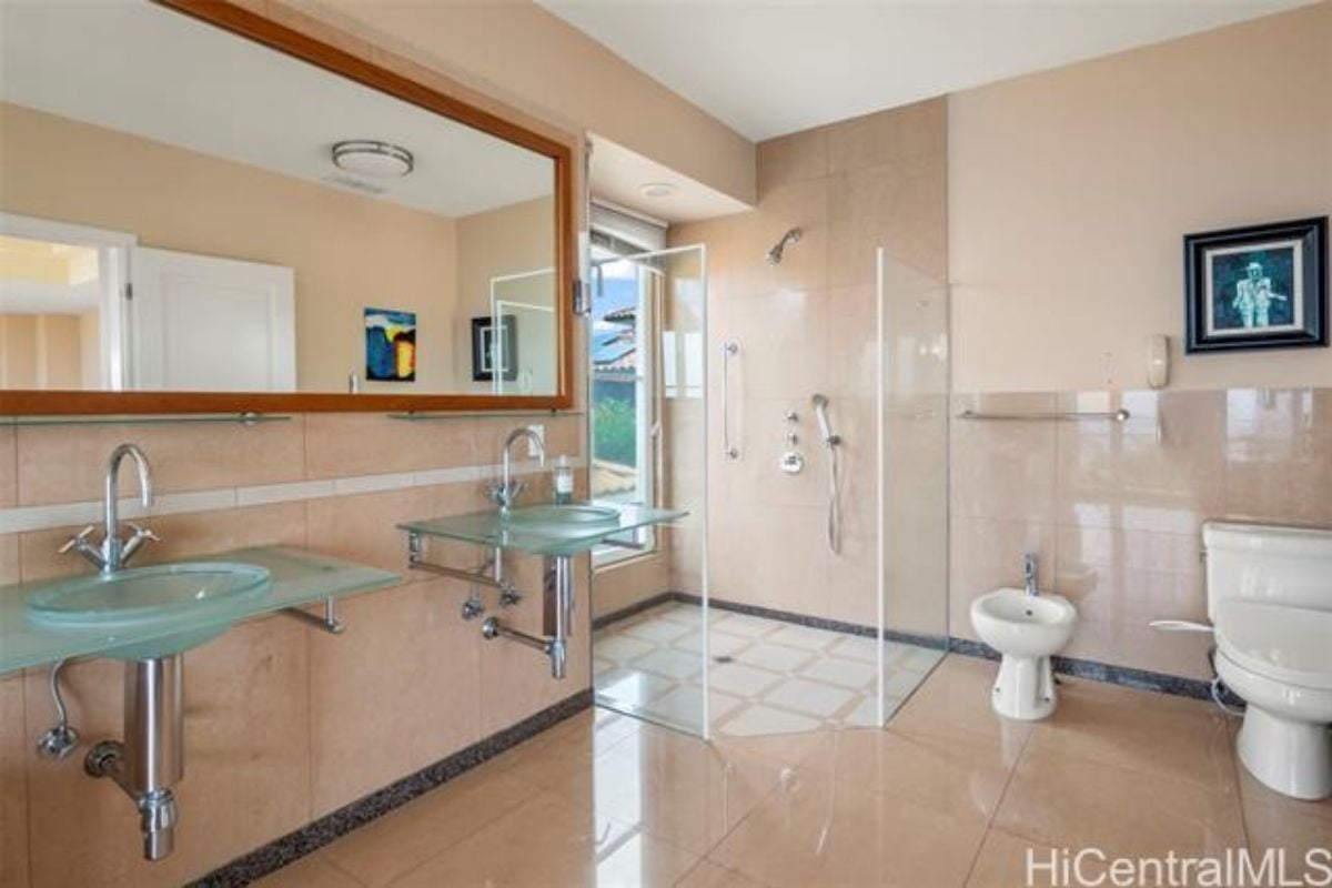 A bathroom with glass vanities, mirror, and a toilet.