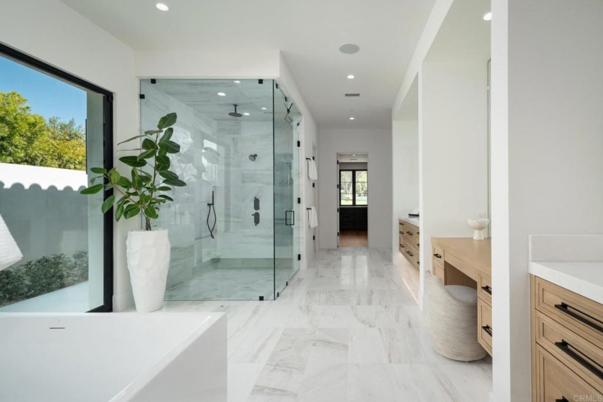 A bathroom with a tiled floor and a glass shower enclosure.