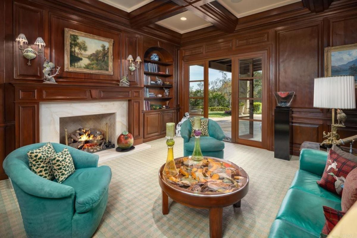 A family room with a painting, a fireplace, a rug, a couch, chairs, and a round coffee table.