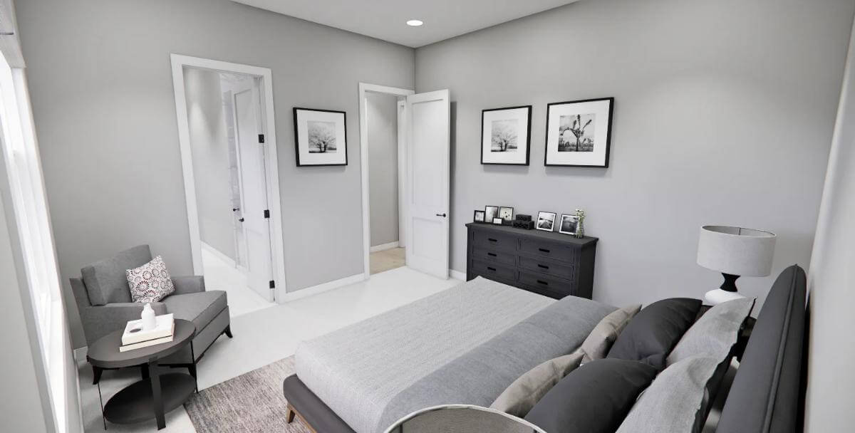 Primary bedroom with an upholstered bed and a cushioned chair over the carpeted floor.