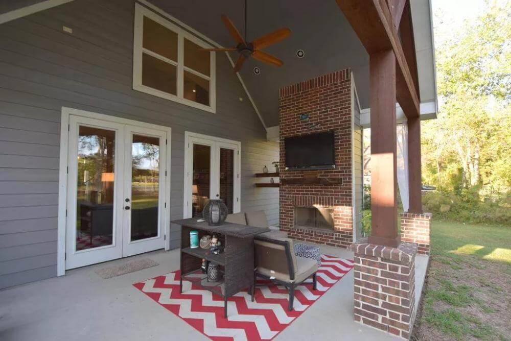 Rear porch with a brick fireplace and an L-shaped sofa over the chevron rug.