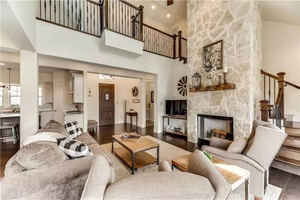 Great room room with a sectional sofa, a wingback chair, and a stone fireplace.