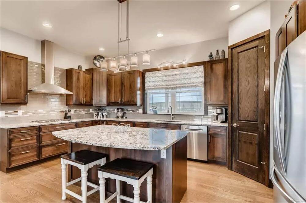 Kitchen with wooden cabinets and a matching island with seating for two.