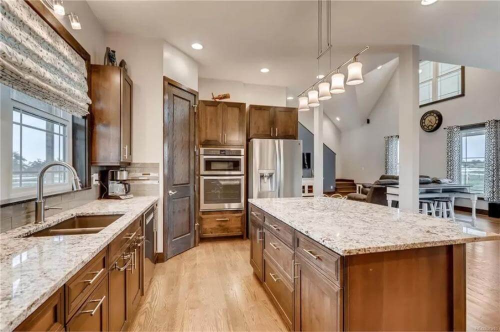 The kitchen includes stainless steel appliances and double sinks set under the windows.