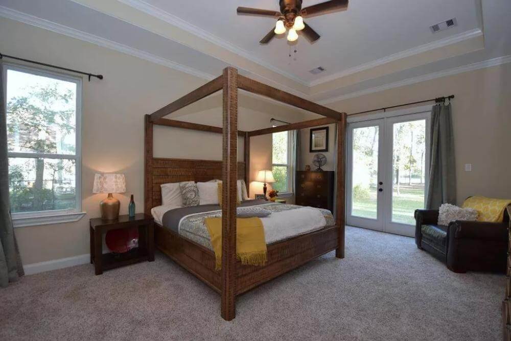 Primary bedroom with outdoor access, a leather chair, and a canopy bed under the step ceiling.