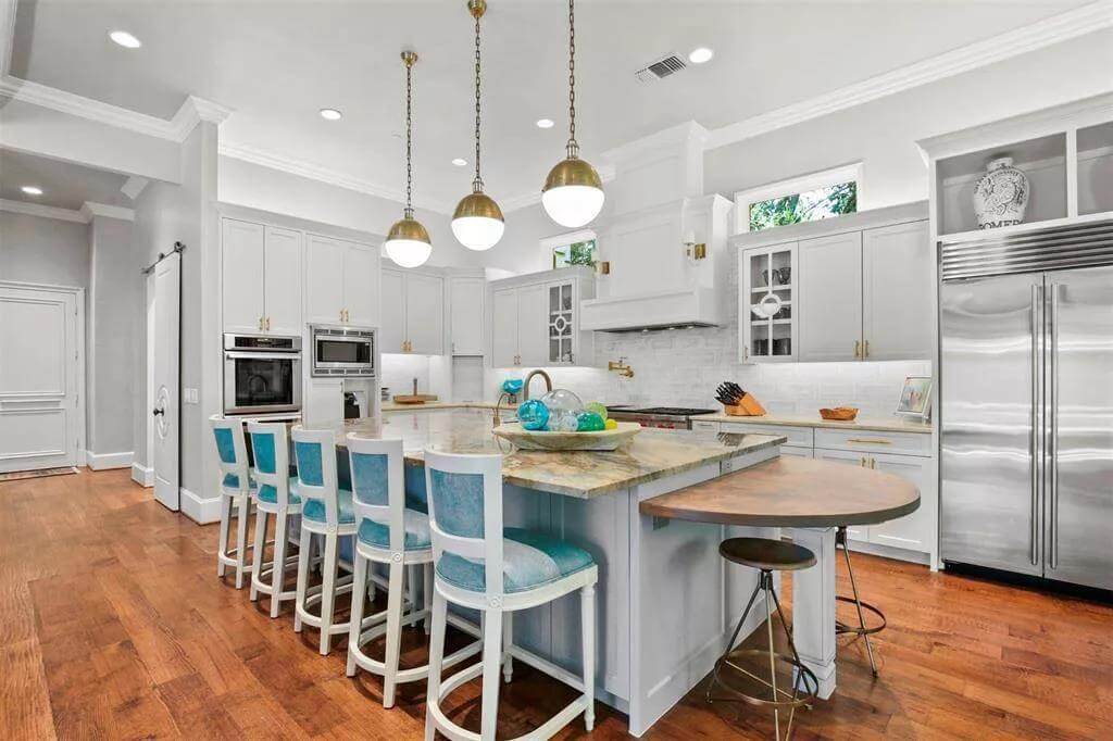 Kitchen with white cabinetry and a center island attached with a snack bar.