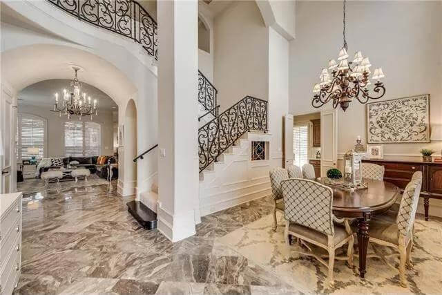 Dining room with cushioned chairs and a dark wood table topped by an ornate chandelier.