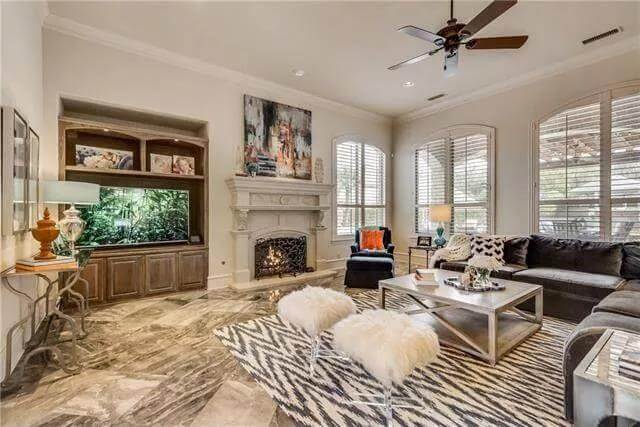 Family room with an L-shaped sofa, furry stools, and a fireplace.
