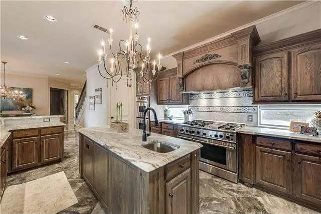 Kitchen with rustic cabinets and a matching island fitted with a prep sink.