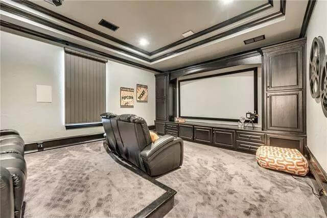 Media room with a step celling and a carpeted floor.