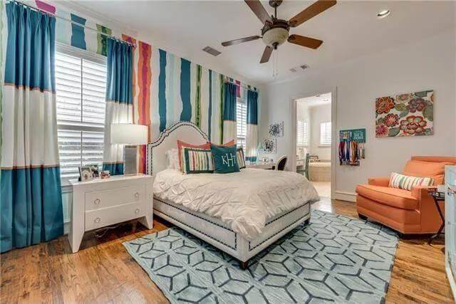 Guest suite with an orange chair and an upholstered bed over the patterned area rug.