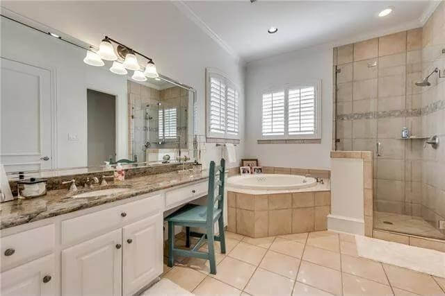 Bathroom with an elongated vanity, a corner tub, and a tiled shower.