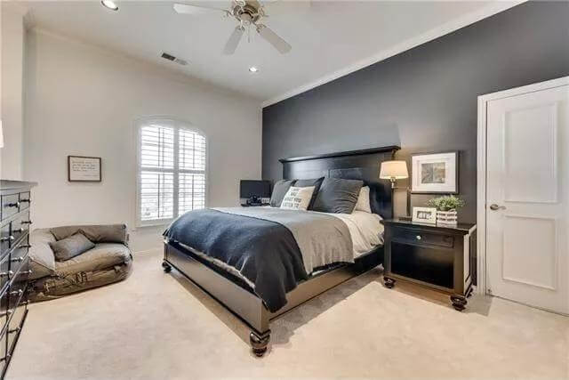 Bedroom with an arched window and a black bed against the black accent wall.
