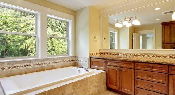 Primary bathroom with a large vanity and a bathtub situated under the windows.