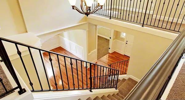 Staircase with wrought iron railings illuminated by a warm chandelier.