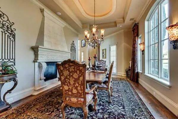Dining room with a fireplace and a wooden dining set illuminated by a warm chandelier.