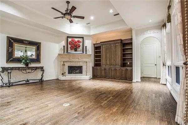 Family room with a tray ceiling, a corner fireplace, and a built-in cabinet.