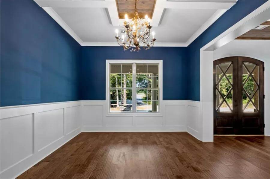 Dining room with a decorative ceiling and blue walls accentuated by white wainscoting.