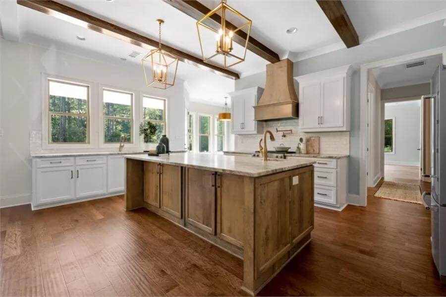 Kitchen with white cabinets and a center island under a beamed ceiling.