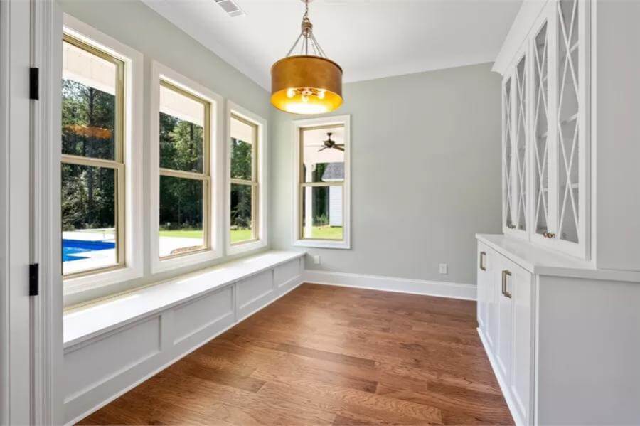 Breakfast nook with a display cabinet and framed windows overlooking the pool.
