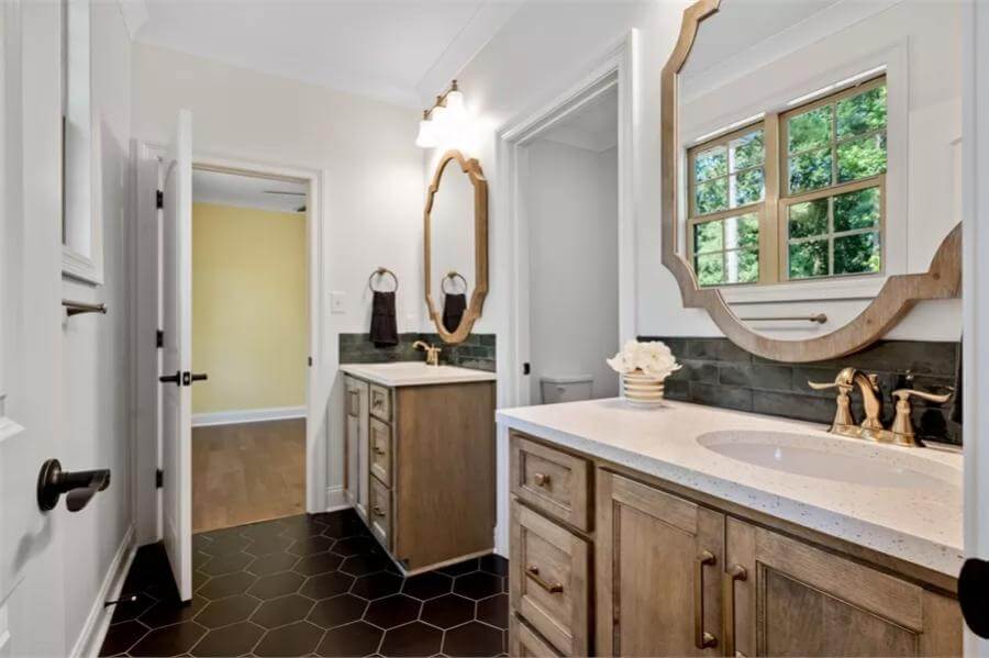Jack and Jill bathroom with his and her vanities and a hex tiled floor.