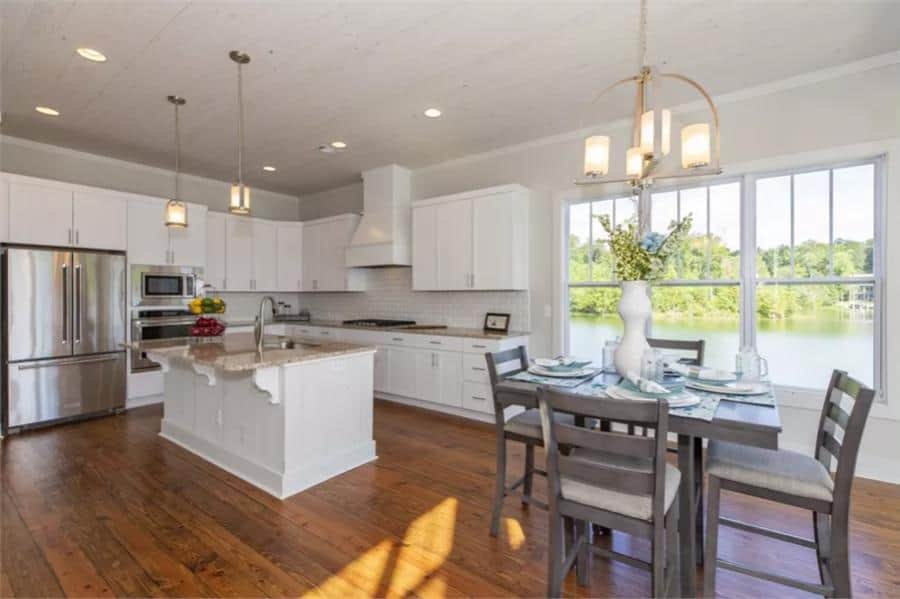 Kitchen and dining area illuminated by warm pendants and recessed ceiling lights.