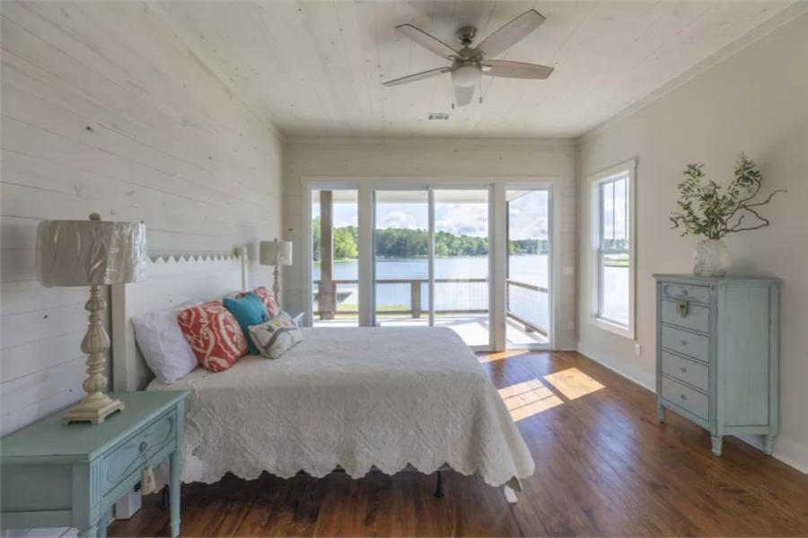 Primary bedroom with a white bed, distressed tables, and a shiplap walls that extend to the ceiling.