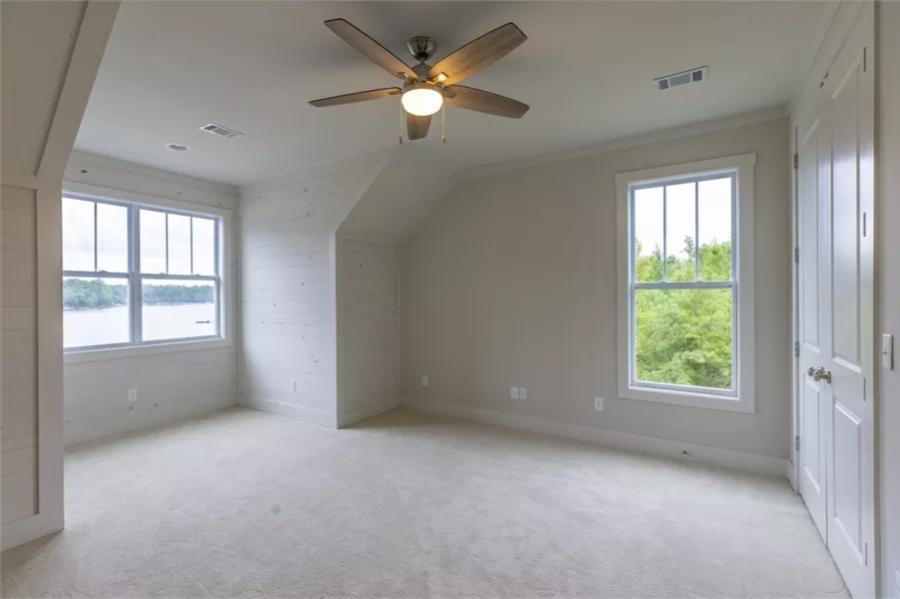 Bedroom with a carpeted floor and white-framed windows.