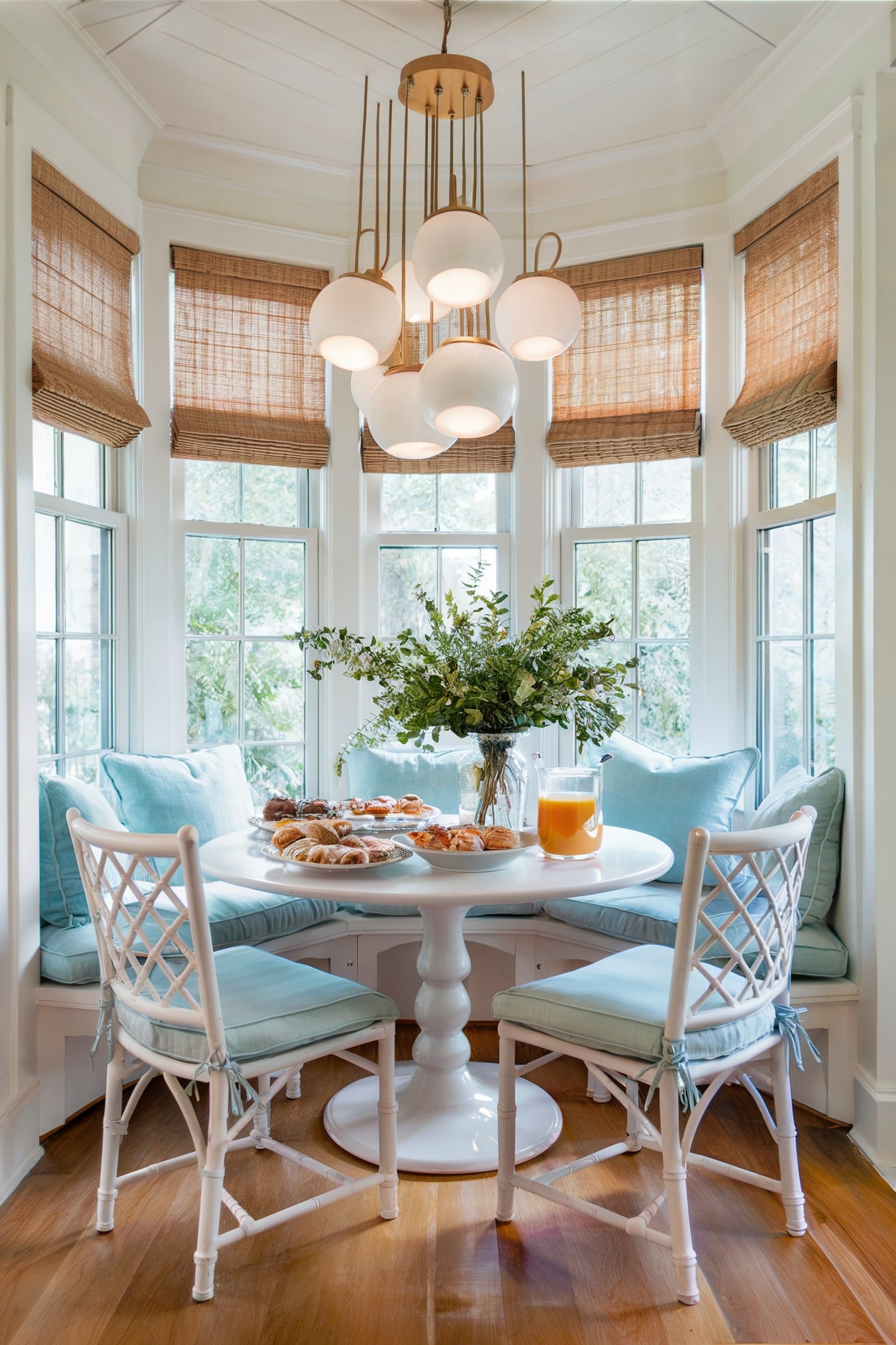 Airy nook with a round table, pastel cushions, and modern lighting surrounded by windows