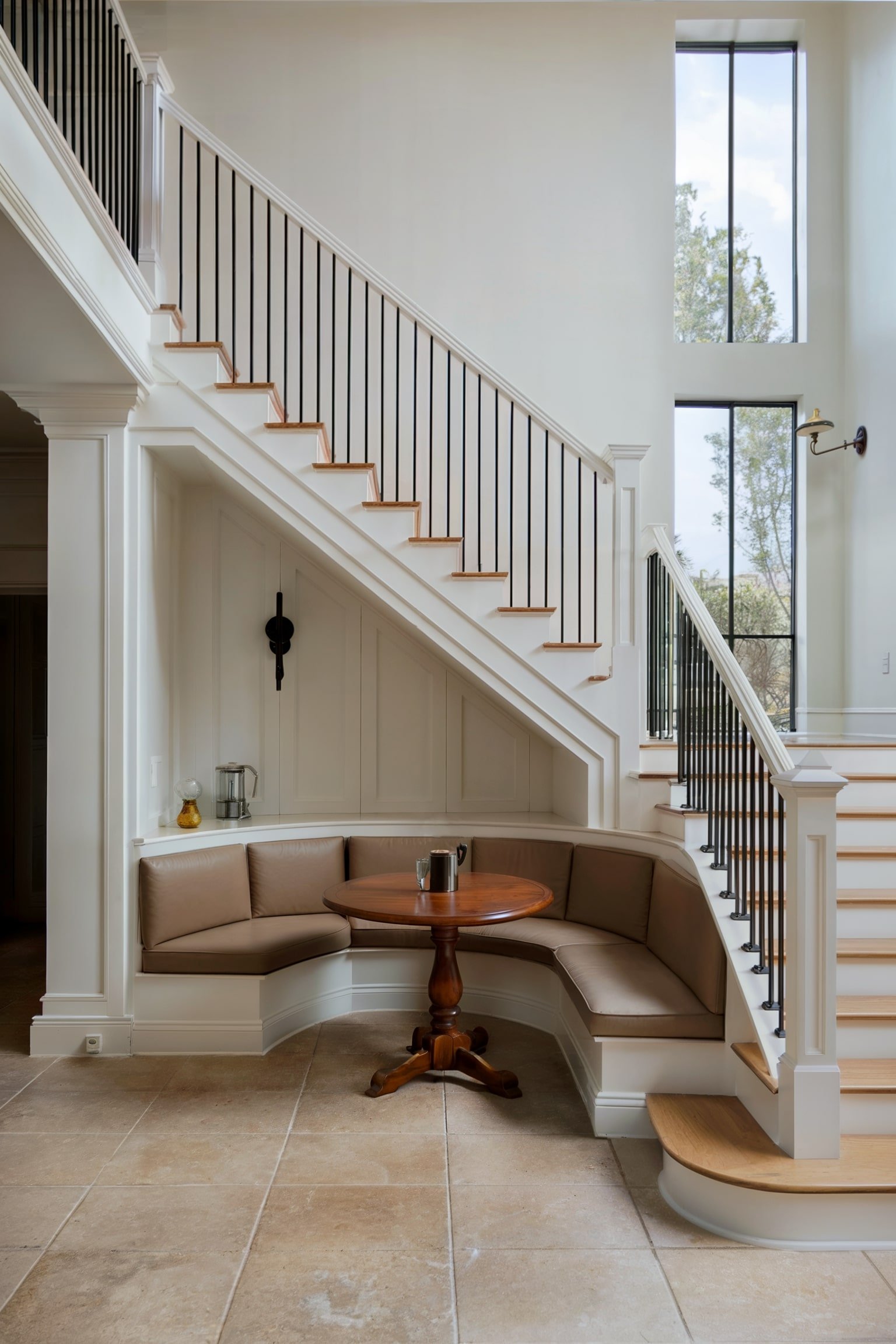 Breakfast nook with a curved bench under the stairs and a round wooden table