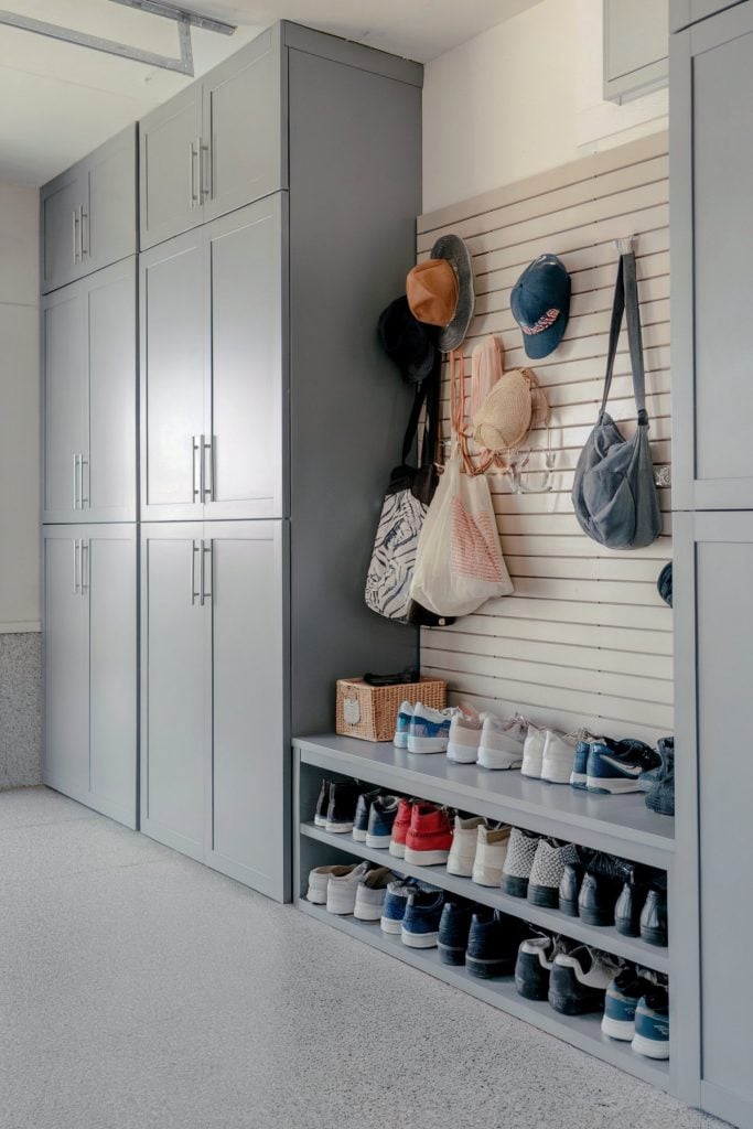 Gray cabinets with a shoe shelf and hooks for hats and bags in a garage