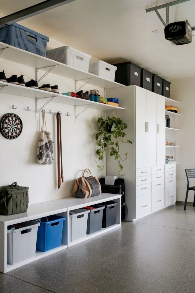 White garage mudroom with shelves, cabinets, hooks, and bins
