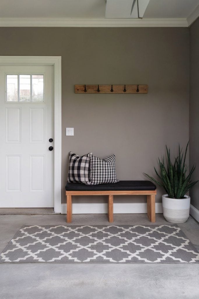 Minimalist mudroom with a bench, pillows, and rug