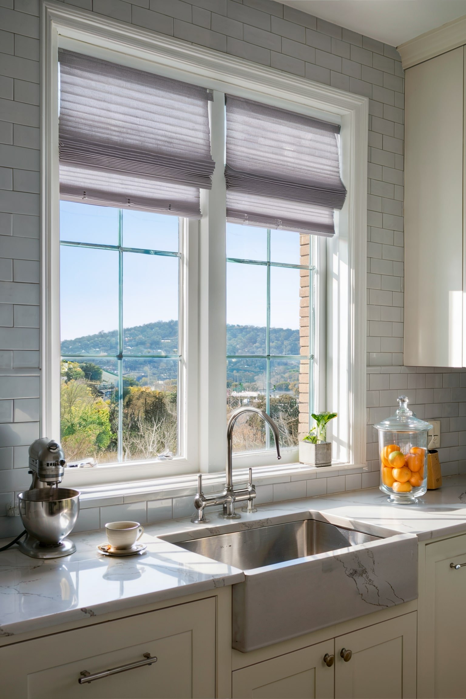Kitchen with Roman shades, gray subway tile backsplash, and a view of the hills outside