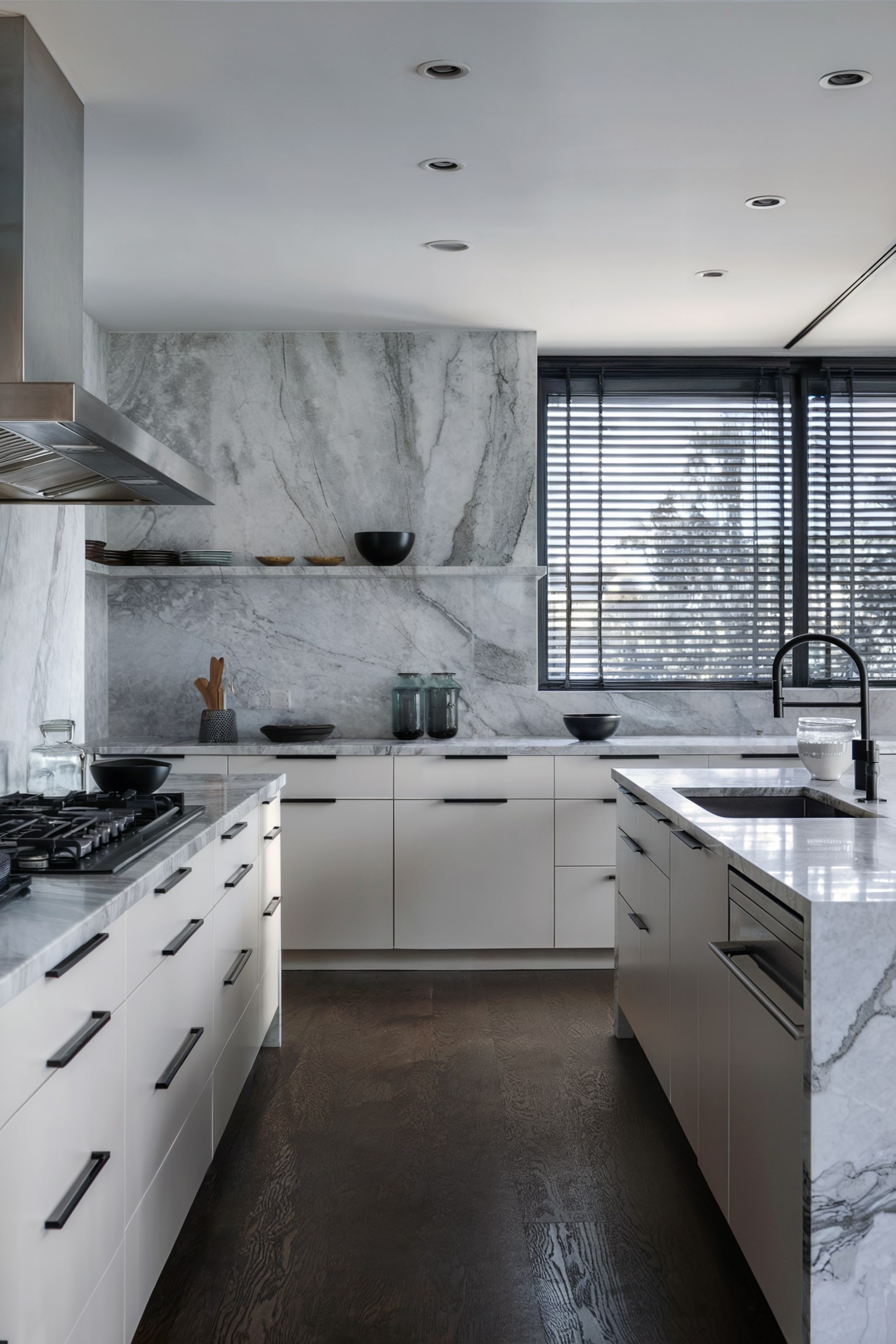 White kitchen with marble walls and dark horizontal blinds on the window