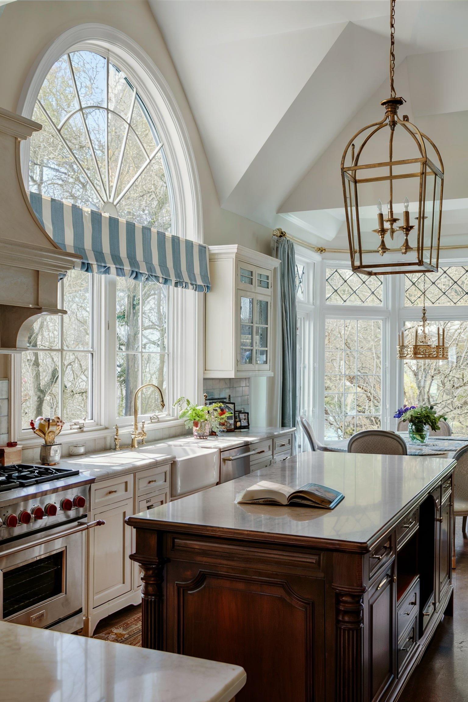Kitchen with arched window and striped blue valance above the sink