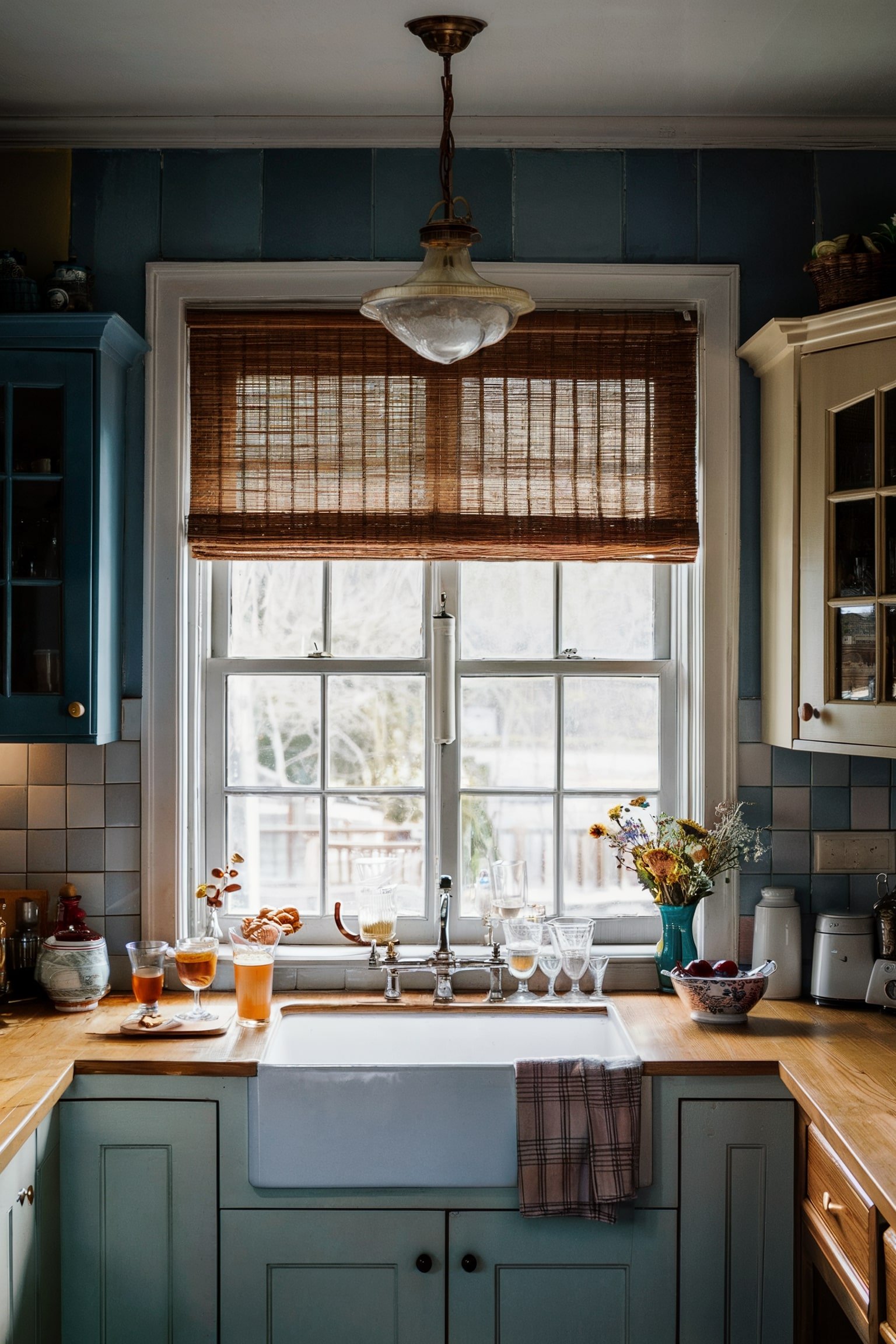 Kitchen with a farmhouse sink, bamboo blinds, and light wood countertops