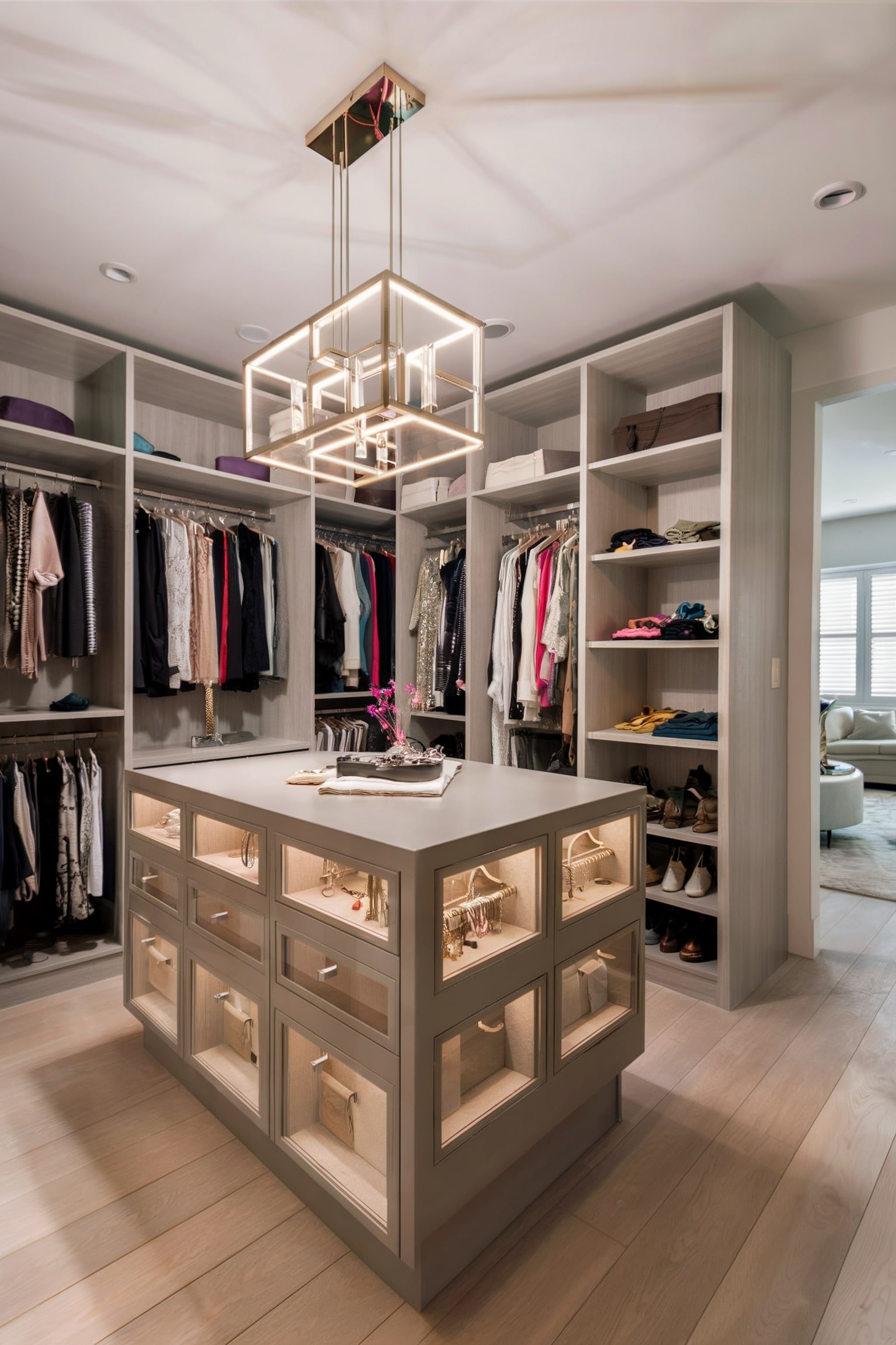 Walk-in closet with lighted island, clothing shelves, and modern chandelier