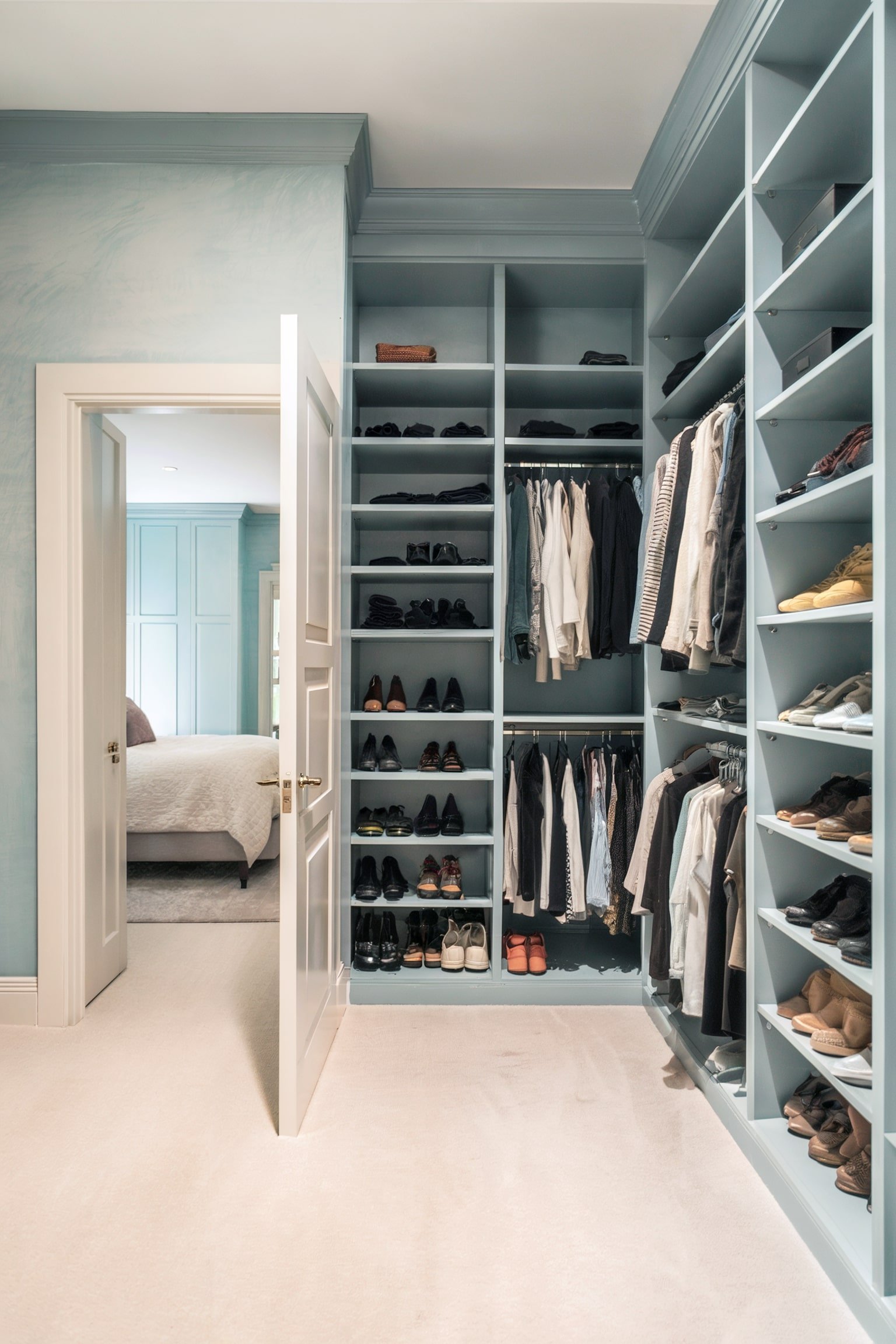 Light blue walk-in closet with organized shelves for shoes and clothes