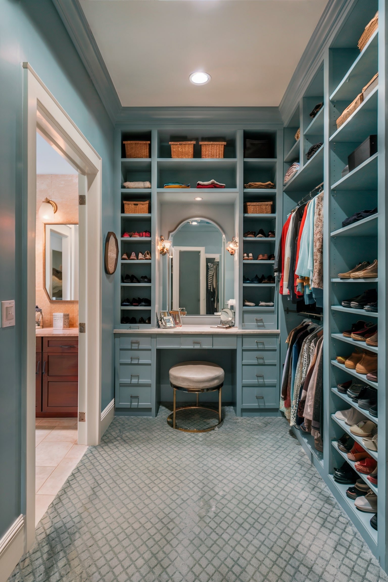 Light blue closet with a vanity and shelves for clothes and shoes