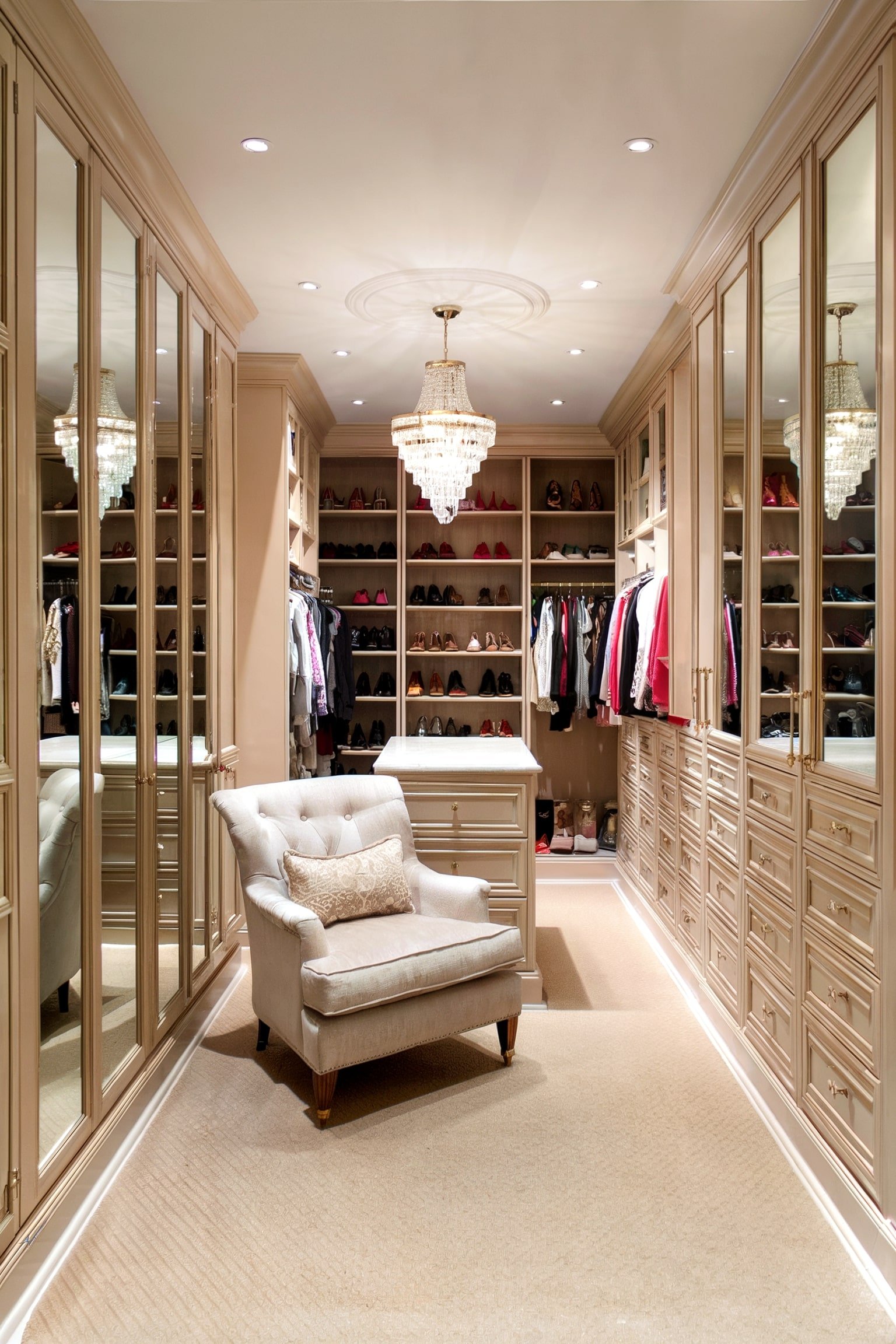 Beige luxury walk-in closet with chandelier and armchair