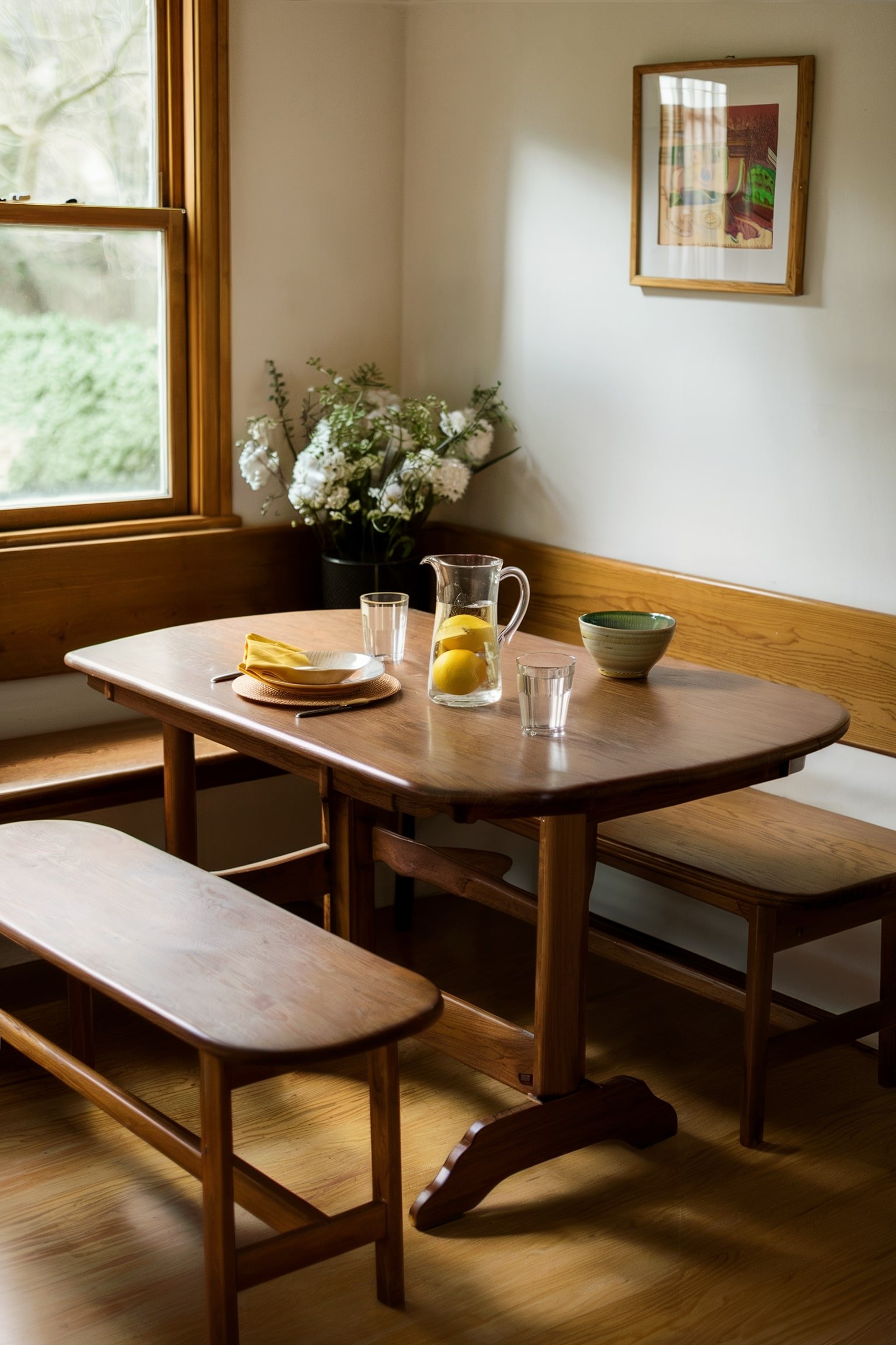 Wooden breakfast nook with a table, benches, and flowers by a window