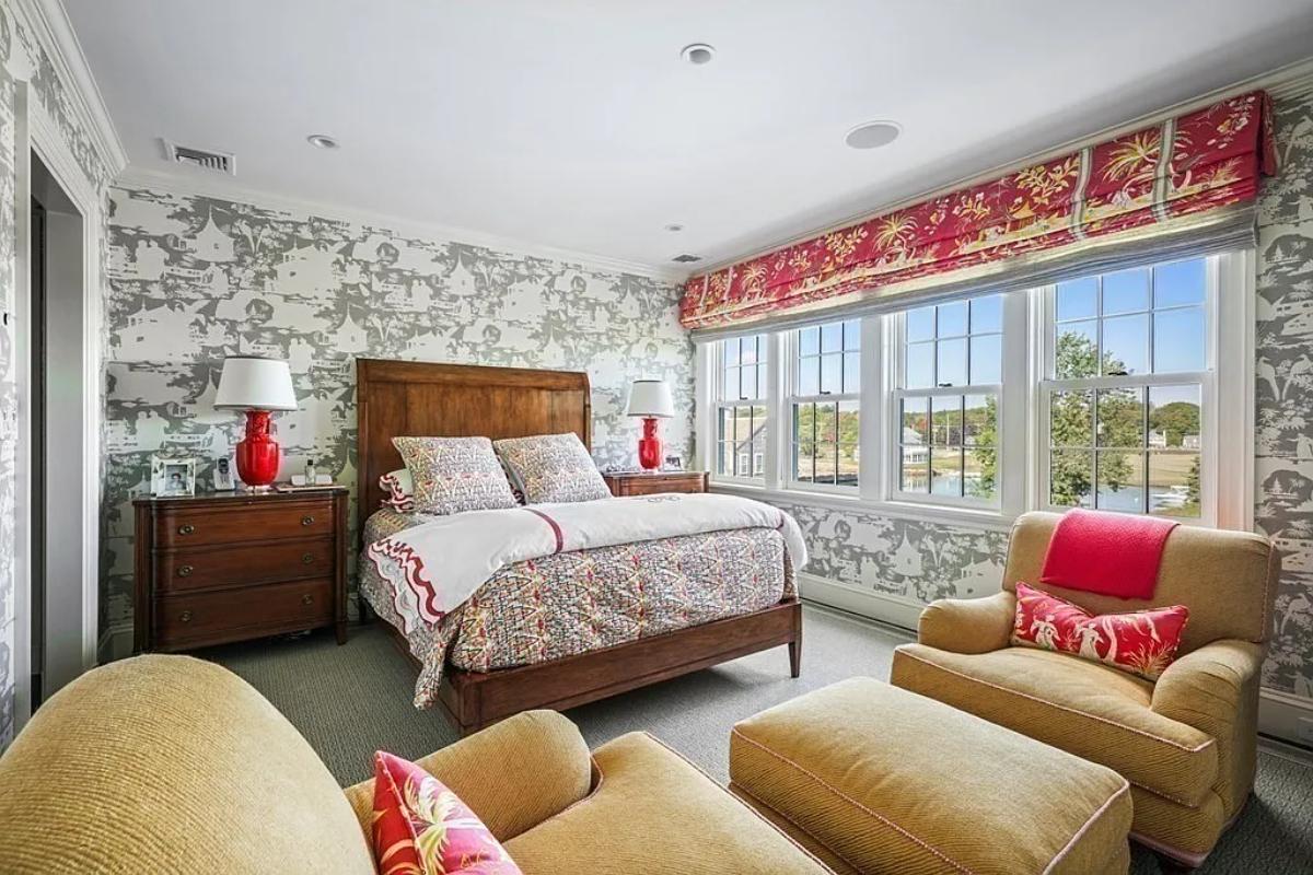 Bedroom with a large bed, couches and carpet flooring.