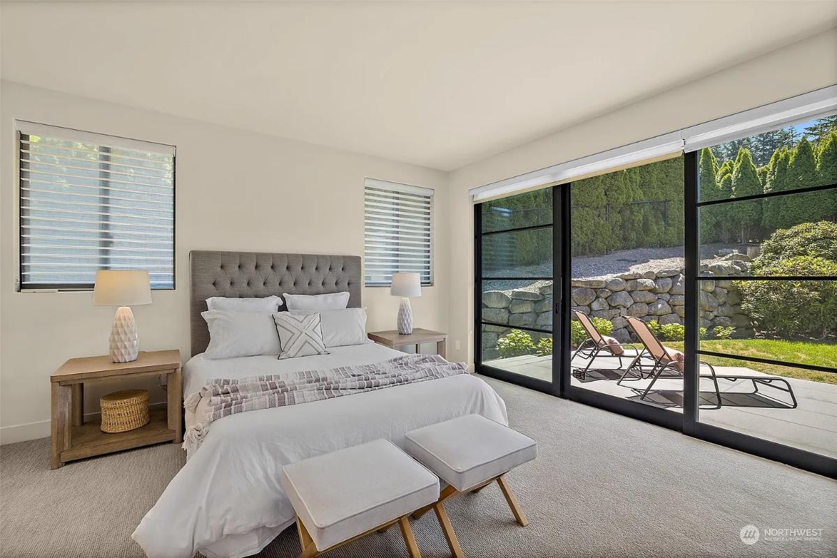 Bedroom with a large bed, sliding glass doors and carpet flooring.