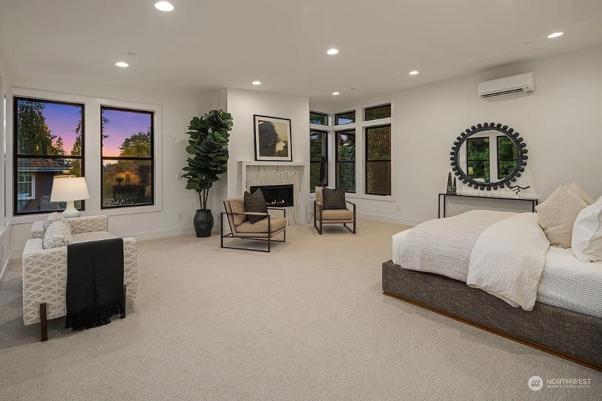 Bedroom with a large bed, fireplace and carpet flooring.
