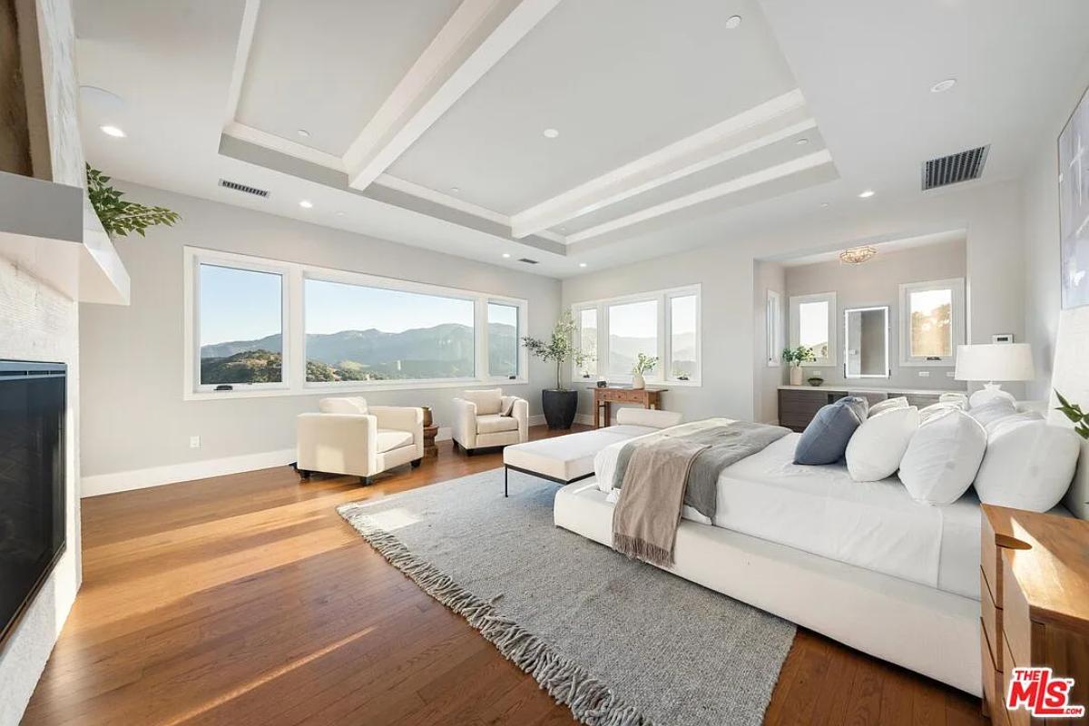 Bedroom with a large bed, glass windows and hardwood floors.