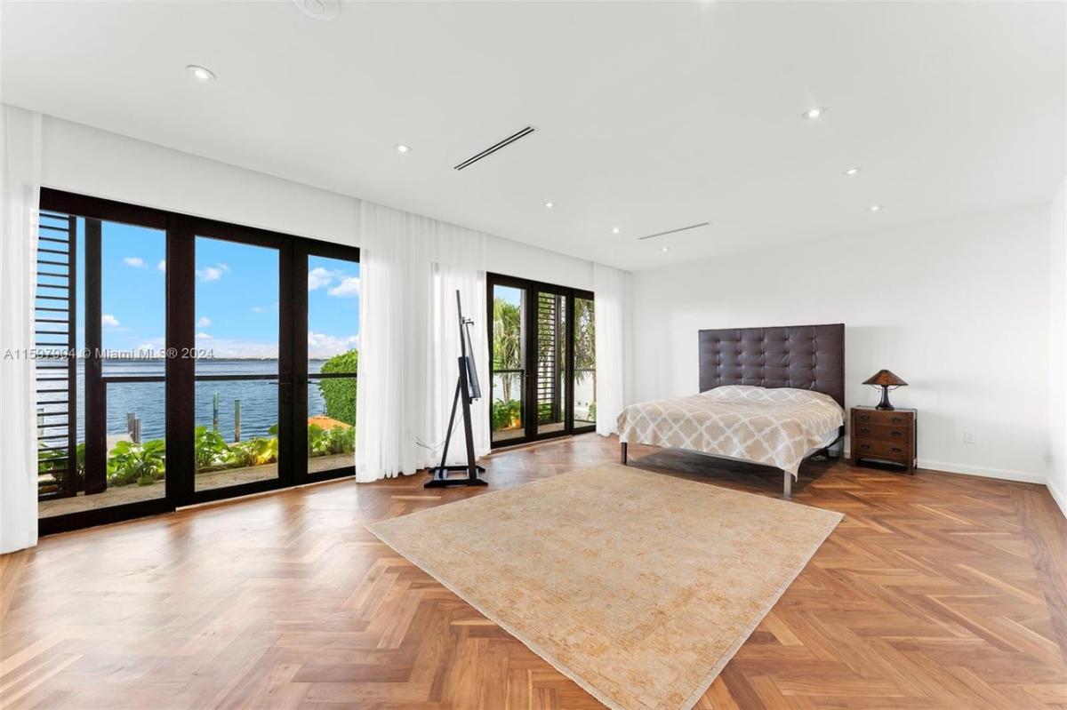Bedroom with a large bed, sliding glass doors and hardwood floors.